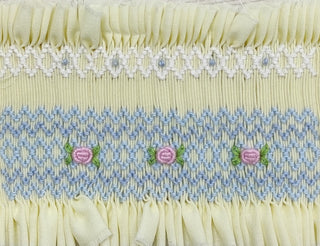 Embroidery details on a pale yellow baby girl smocked set with puff sleeves, pastel embroidery, and matching ruffle bloomers, ideal for spring occasions.