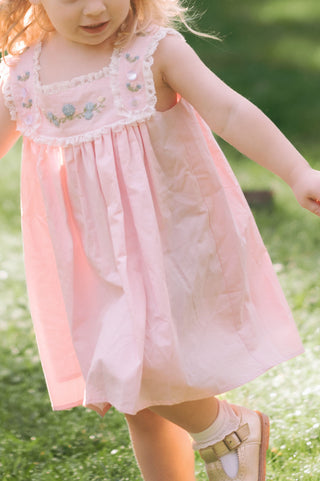 Toddler girl in a light pink heirloom dress with hand-embroidered hydrangeas and delicate lace trim, perfect for spring and Easter.